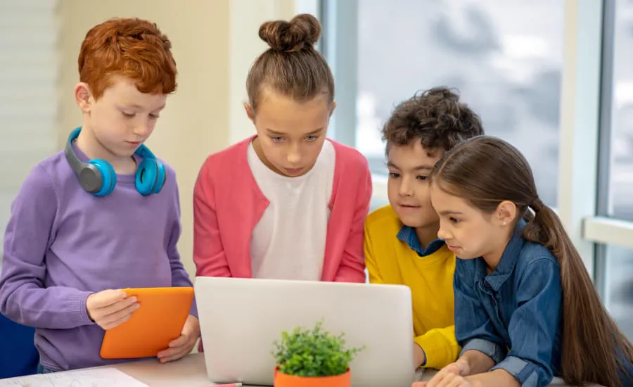 Four children of different ages look at a laptop together