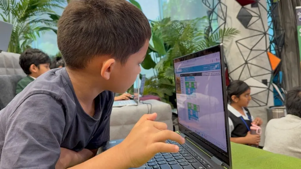 A young student builds a block-based coding project on a laptop at Code Battle 2025