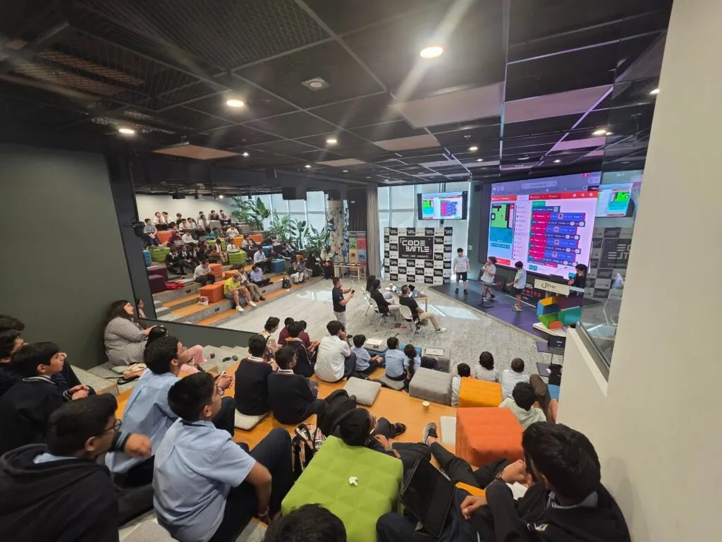 A student team presents its project on the big screen at Code Battle 2025 in DTEC Dubai