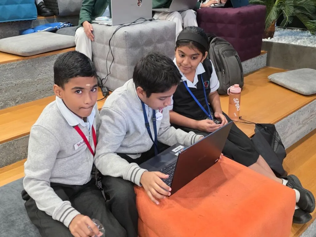 Three young students building their project together on a laptop at Code Battle 2025