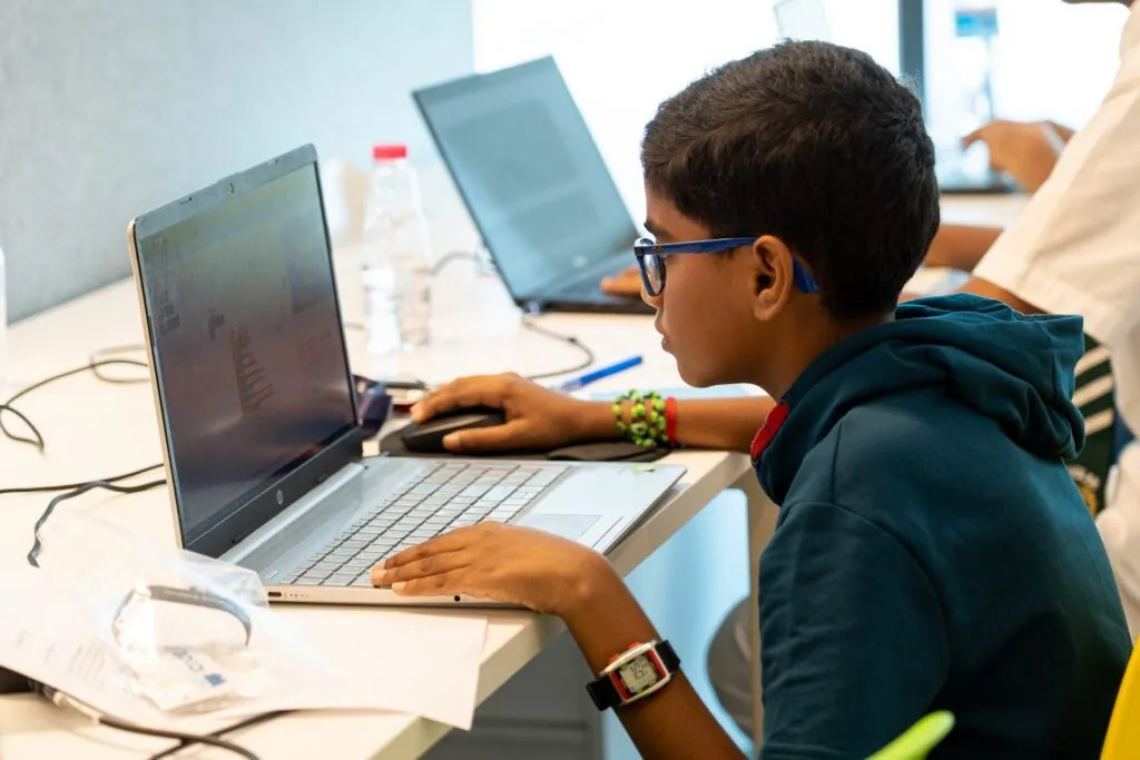 A young student builds a coding project on a laptop at CodeNova 2022 in Sharjah