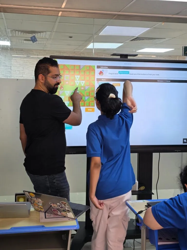 A student points to a Scratch project on the classroom screen during iCodejr's coding programme at Behaviour Enrichment