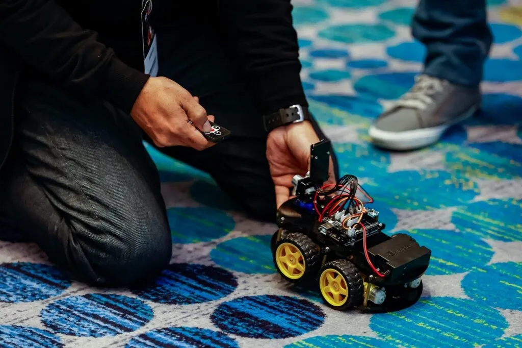 An iCodejr instructor sets up a remote-controlled robot car on the floor