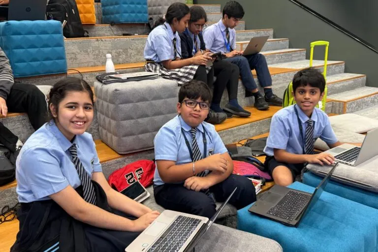 Three smiling school students with their laptops at Code Battle 2025, iCodejr's inter-school hackathon